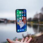 silver iPhone X floating over open palm