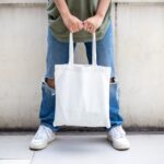 person in blue denim jeans holding white tote bag