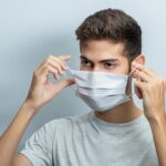 man in gray crew neck t-shirt covering his face with white textile