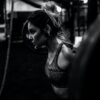 greyscale photo of woman in bralette inside room