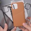 person holding orange leather smartphone case