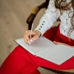 woman in white long sleeve shirt writing on white paper